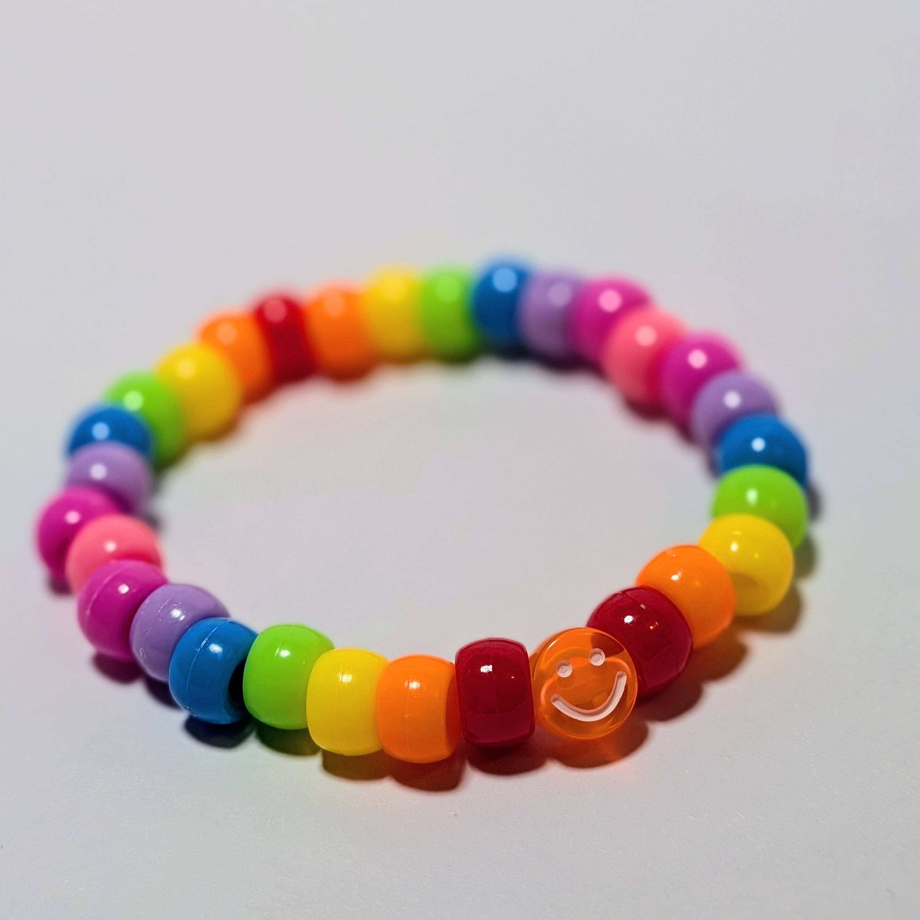 a smiley bead surrounded by a rainbow of thick beads