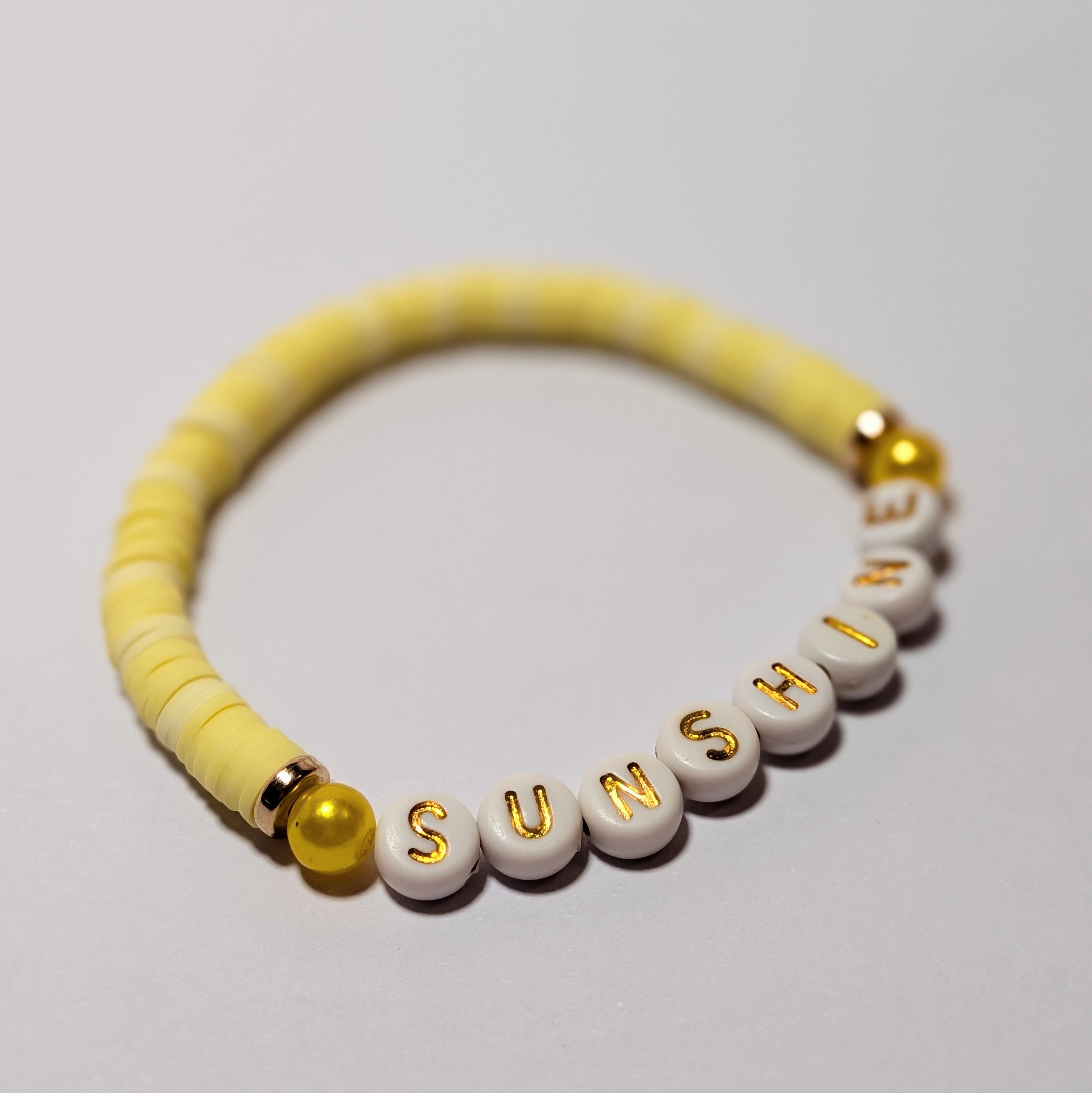  "SUNSHINE" surrounded by matching and contrasting clay beads.