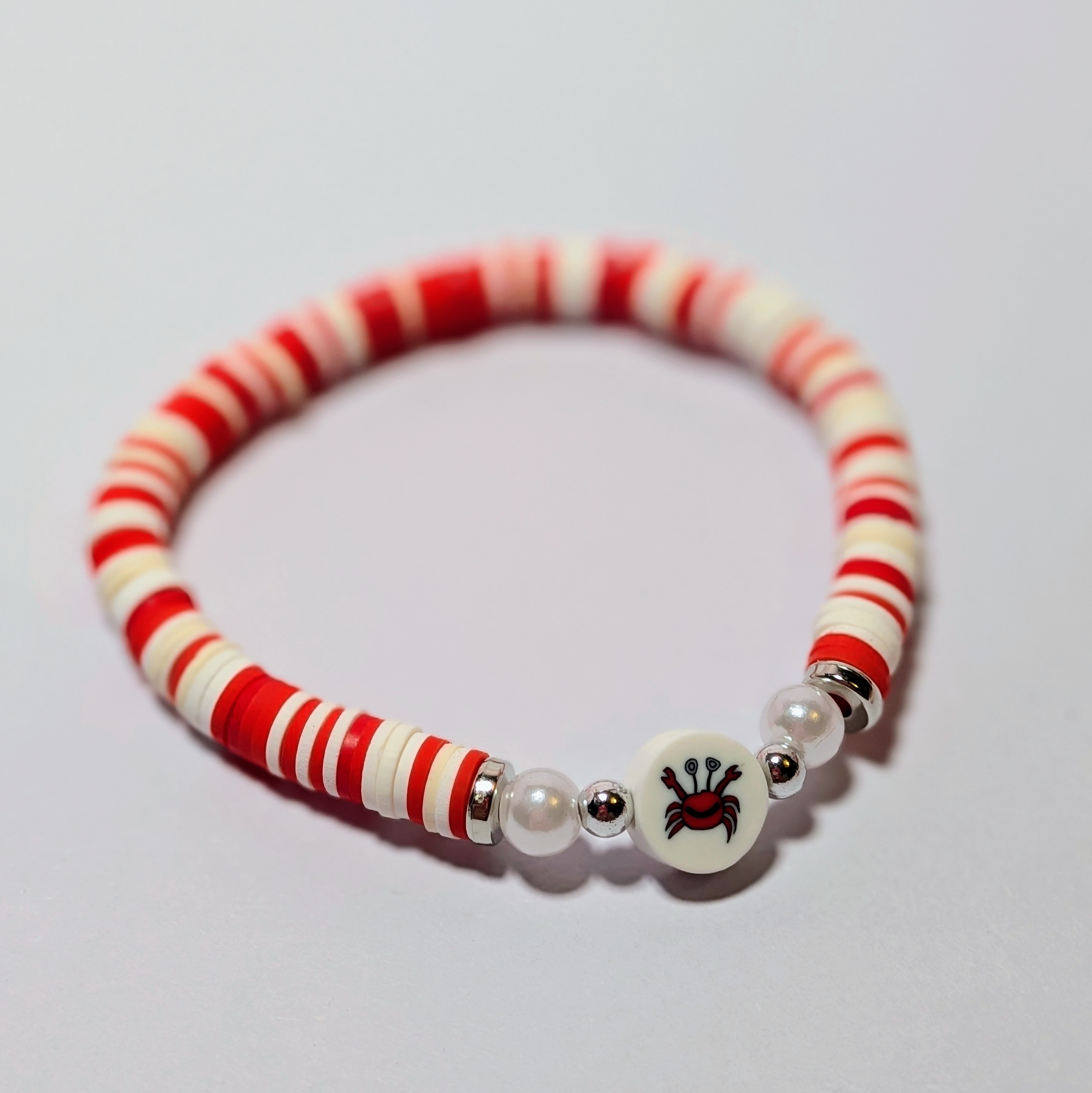 Red and cream clay beads with pearl accents surrounding a cute crab bead