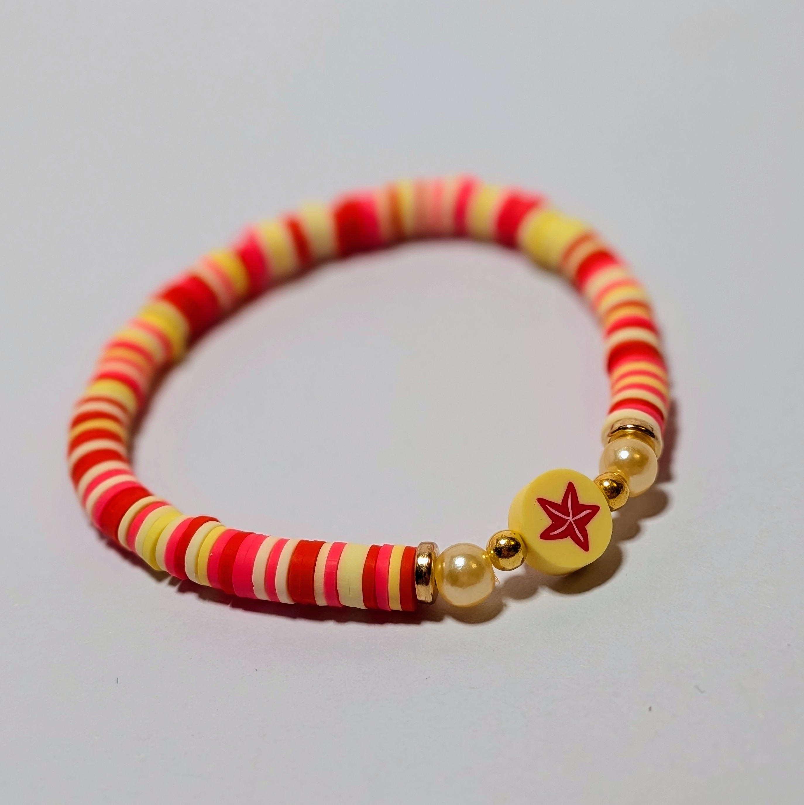 Red and yellow clay beads with pearl accents surrounding a cute starfish bead