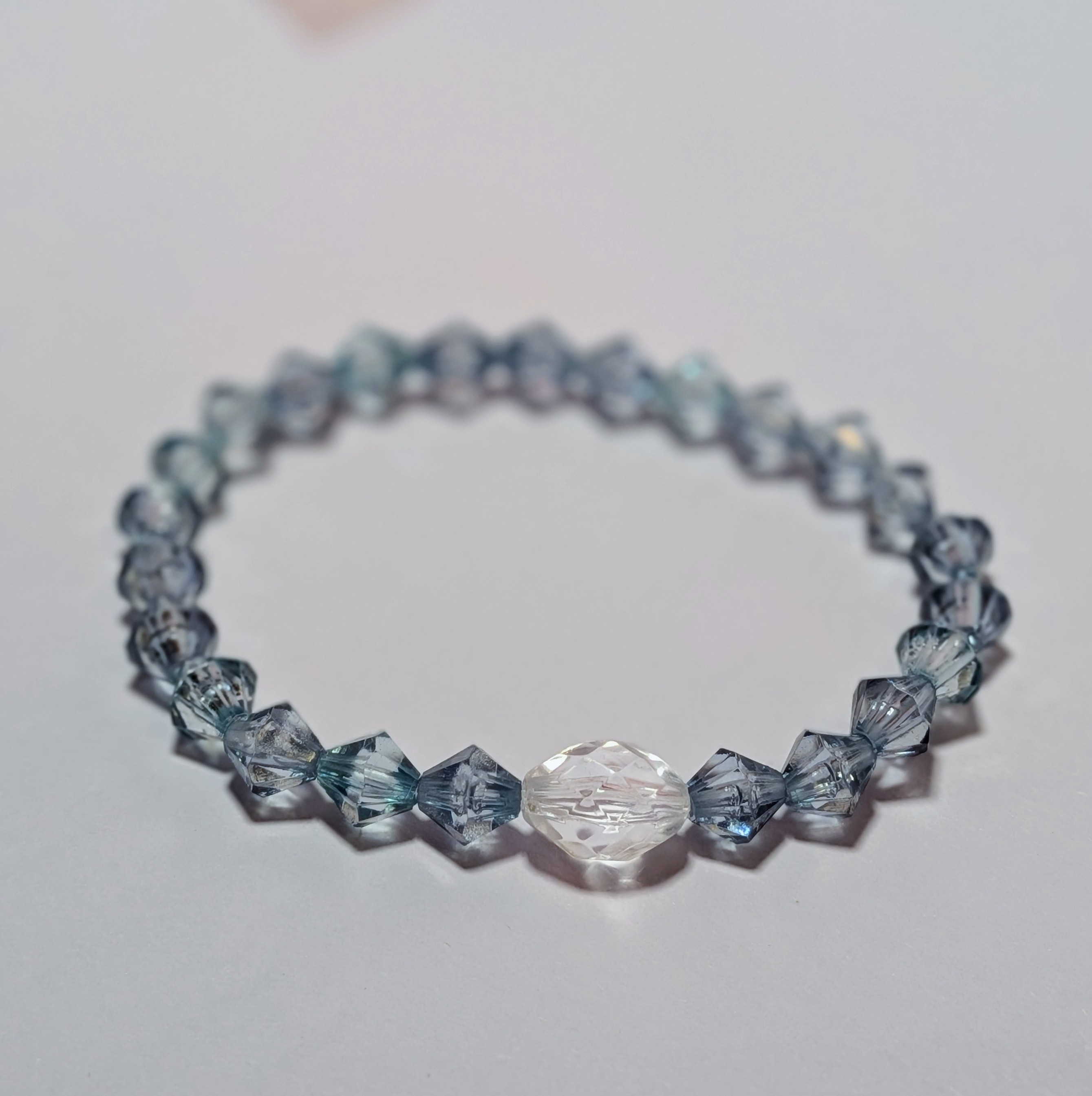  a larger clear glass like bead surrounded by smaller silver glass like beads