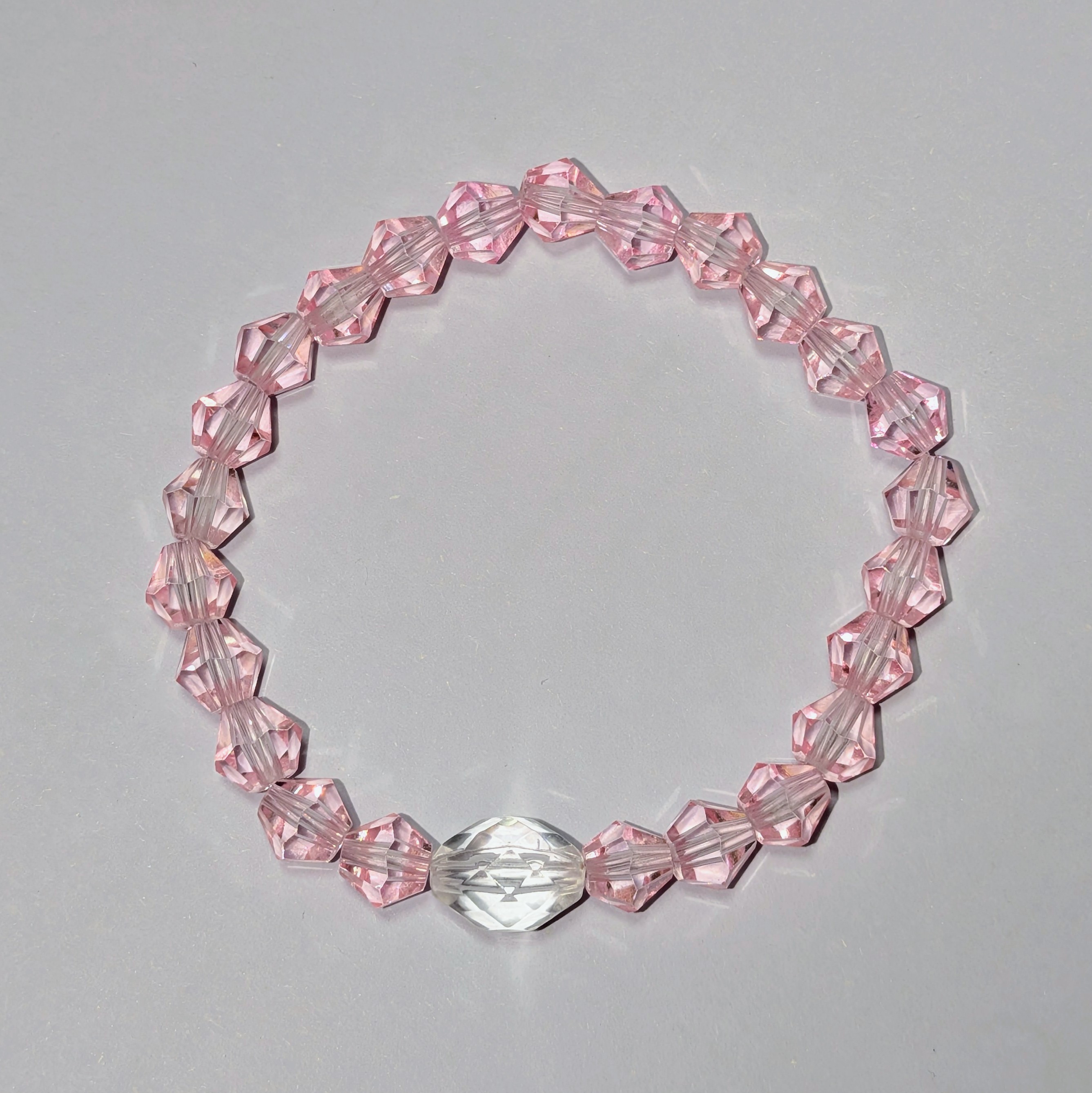  a larger clear glass like bead surrounded by smaller pink glass like beads