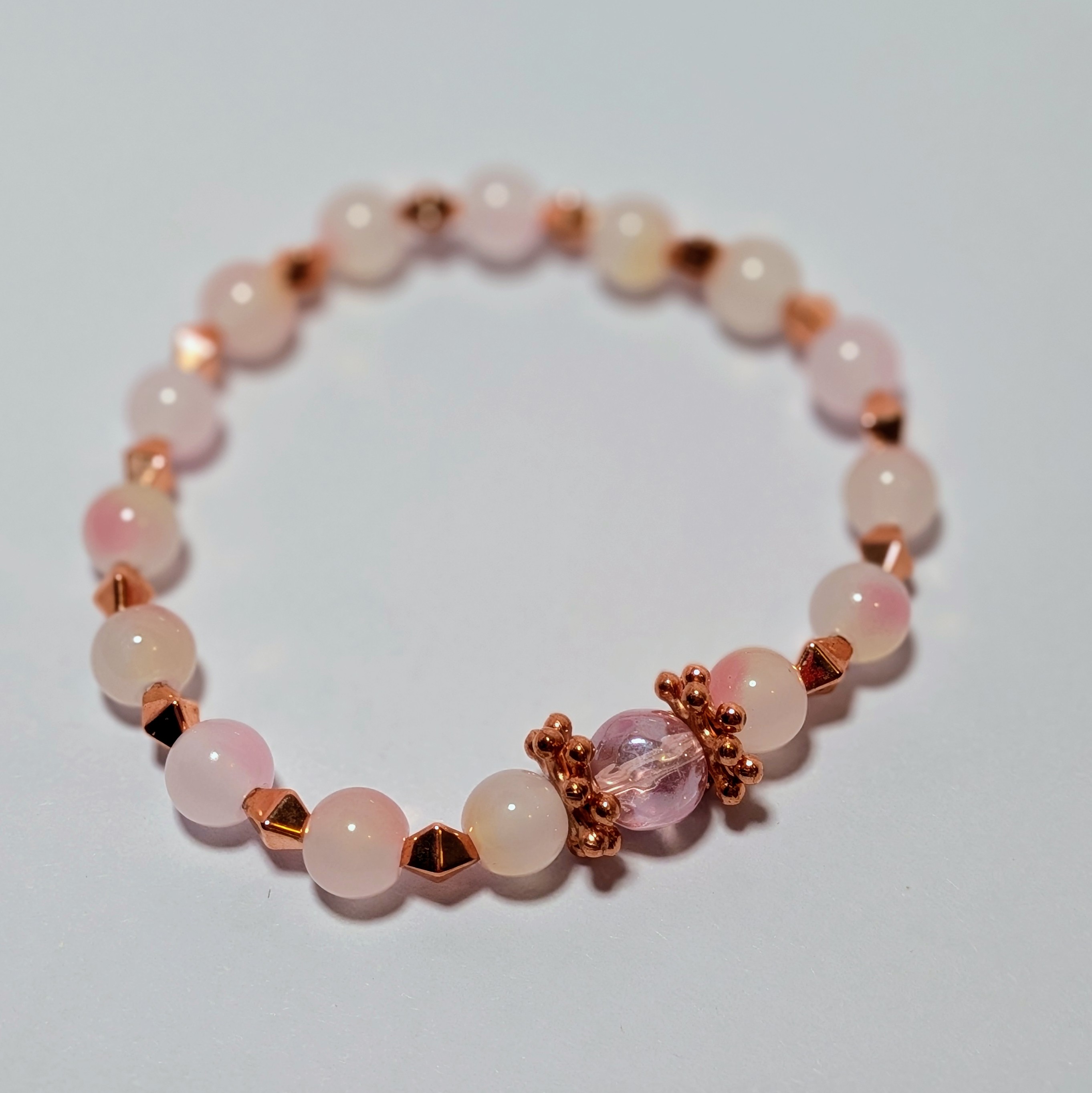 a pearl and marble like beads surrounded by rose gold accents
