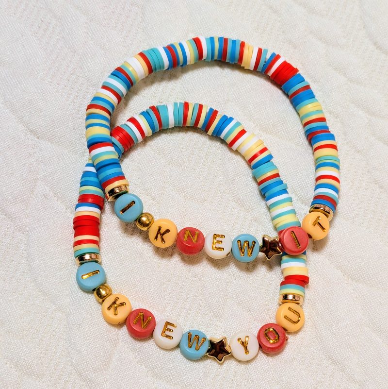 Clay beads in white, red, blue and yellow, with gold accents and letter beads. One says 