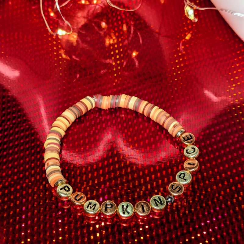 A bracelet that says "Pumpkin spice" in gold and bronze letters, with clay beads and gold spacers — view 3