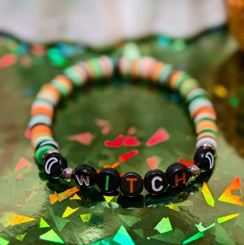 Halloween friendship bracelet that spells witch with green, white, black and orange beads — view 2