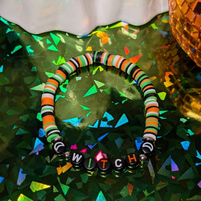 Halloween friendship bracelet that spells witch with green, white, black and orange beads — view 3