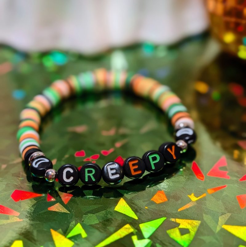 Halloween friendship bracelet that spells creepy with green, white, black and orange beads — view 2