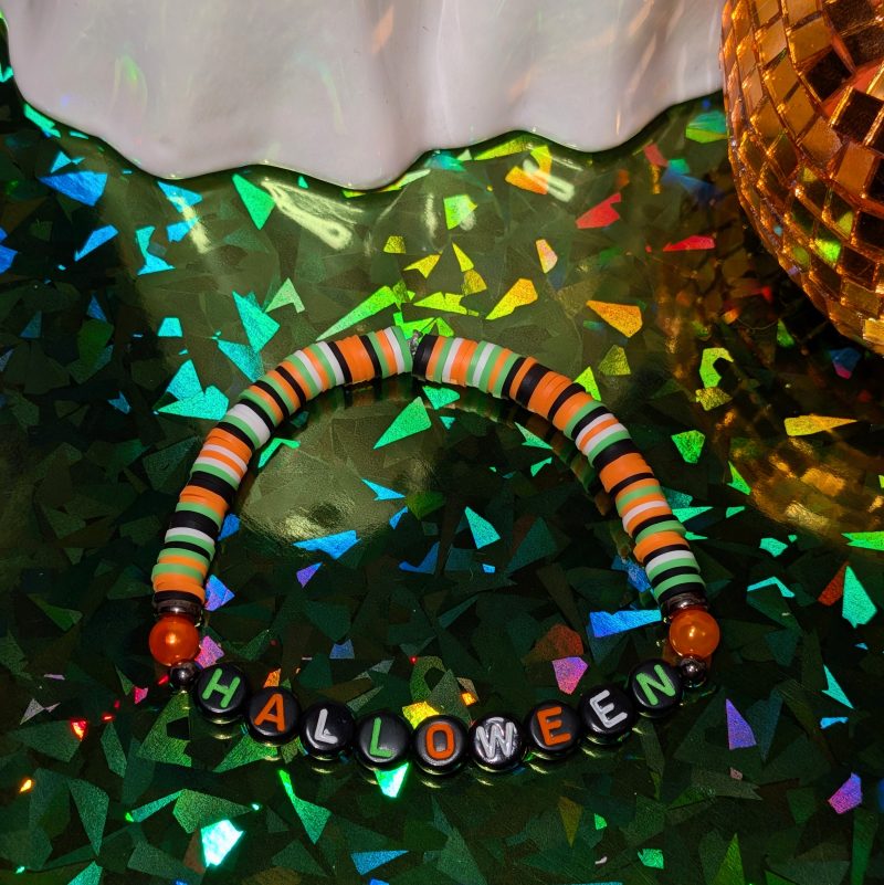 friendship bracelet that spells Halloween with green, white, black and orange beads — view 3