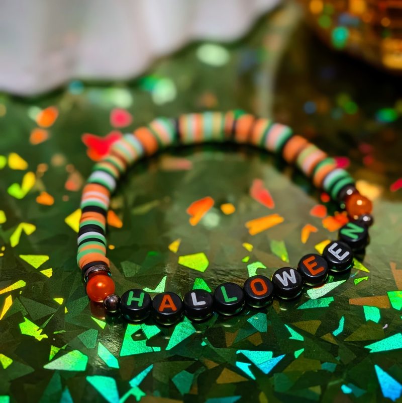 friendship bracelet that spells Halloween with green, white, black and orange beads — view 2