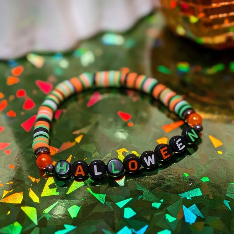 friendship bracelet that spells Halloween with green, white, black and orange beads
