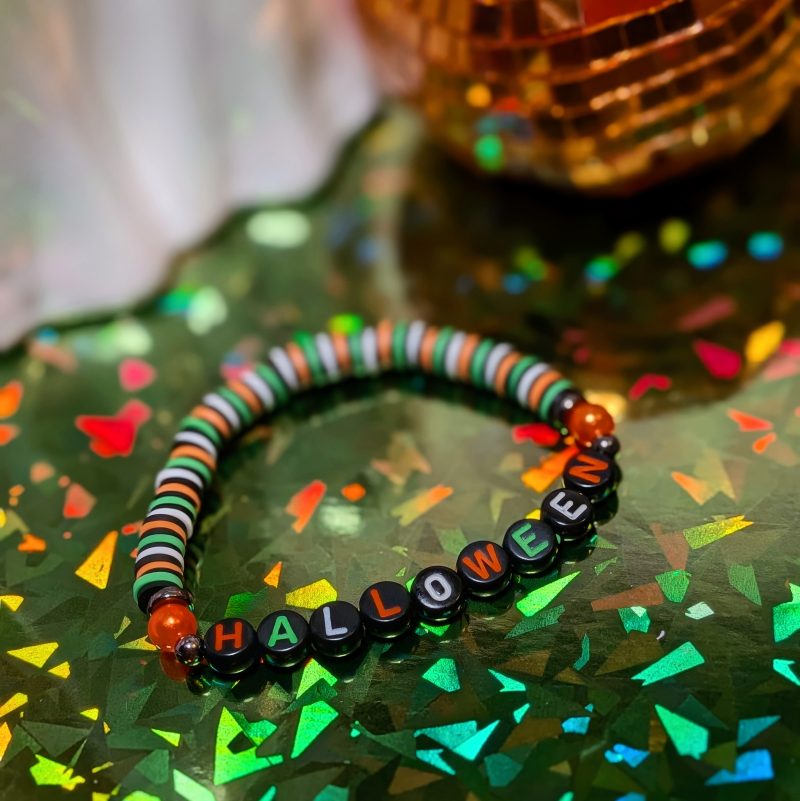 friendship bracelet that spells Halloween with green, white, black and orange beads