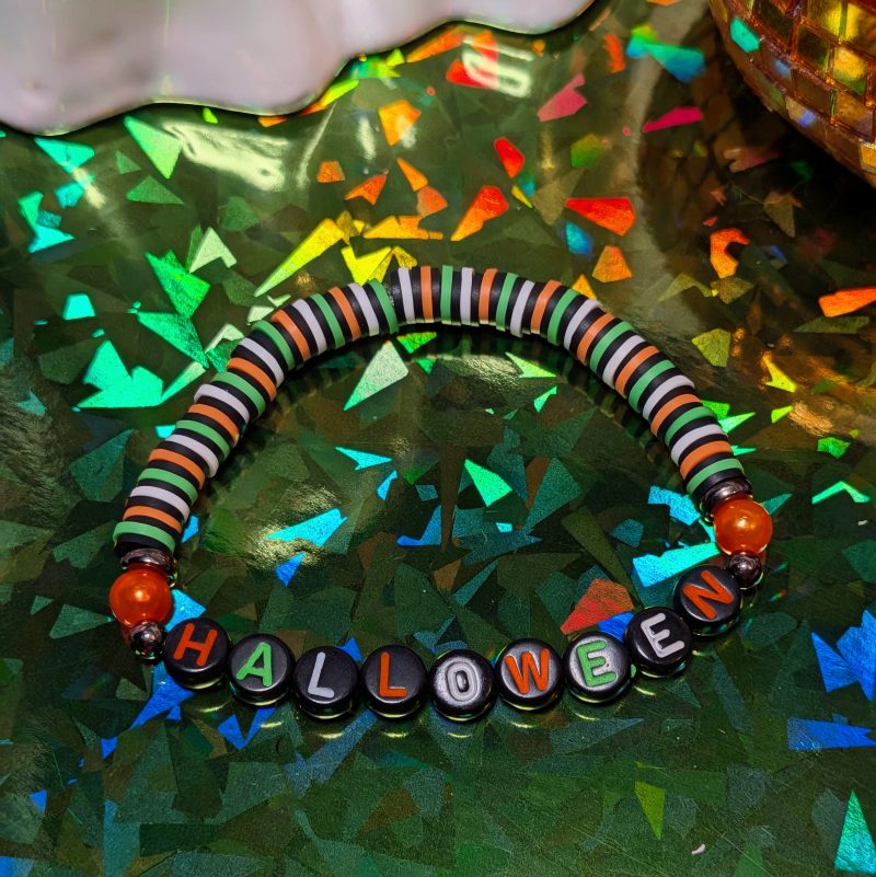 friendship bracelet that spells Halloween with green, white, black and orange beads — view 4
