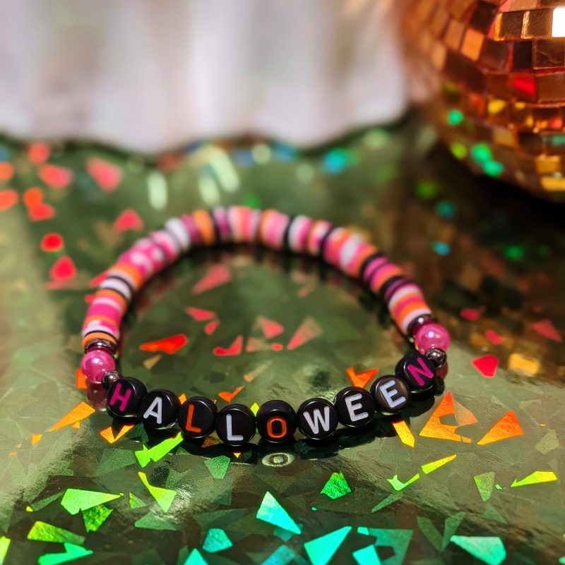 friendship bracelet that spells Halloween with pink, orange, white, and black beads — view 2