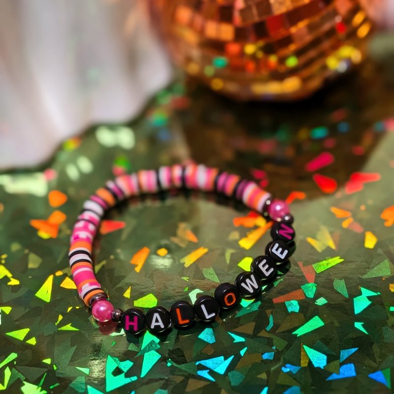 friendship bracelet that spells Halloween with pink, orange, white, and black beads